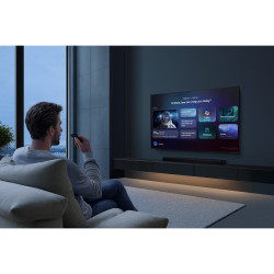 SAMSUNG TMR55R85H TV 55 pouces, mise en situation salon mural avec utilisateur et télécommande