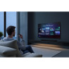 SAMSUNG TMR55R85H TV 55 pouces, mise en situation salon mural avec utilisateur et télécommande